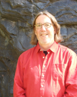 Frank Magilligan smiling with a stone wall in the background